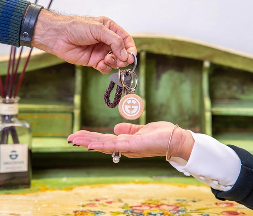 Primo piano di una persona che consegna le chiavi di casa a un'altra in un ambiente accogliente.