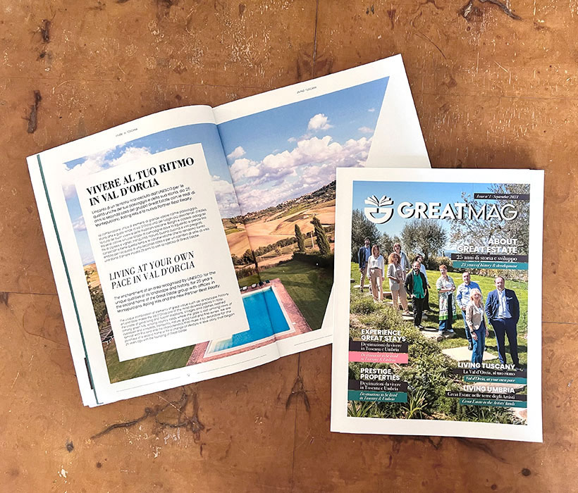 Rivista GreatMag con articolo immobiliare e vista panoramica sulla piscina su tavolo rustico.