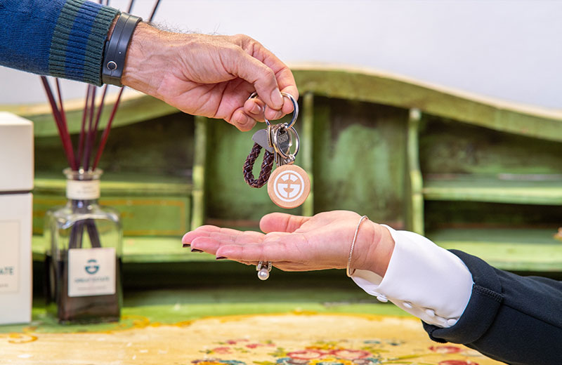 Primo piano della consegna delle chiavi di casa con portachiavi Great Estate in ufficio.