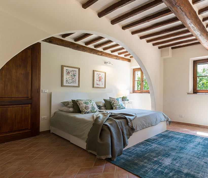 Camera accogliente con travi in legno, arco, arredamento moderno e luce naturale.