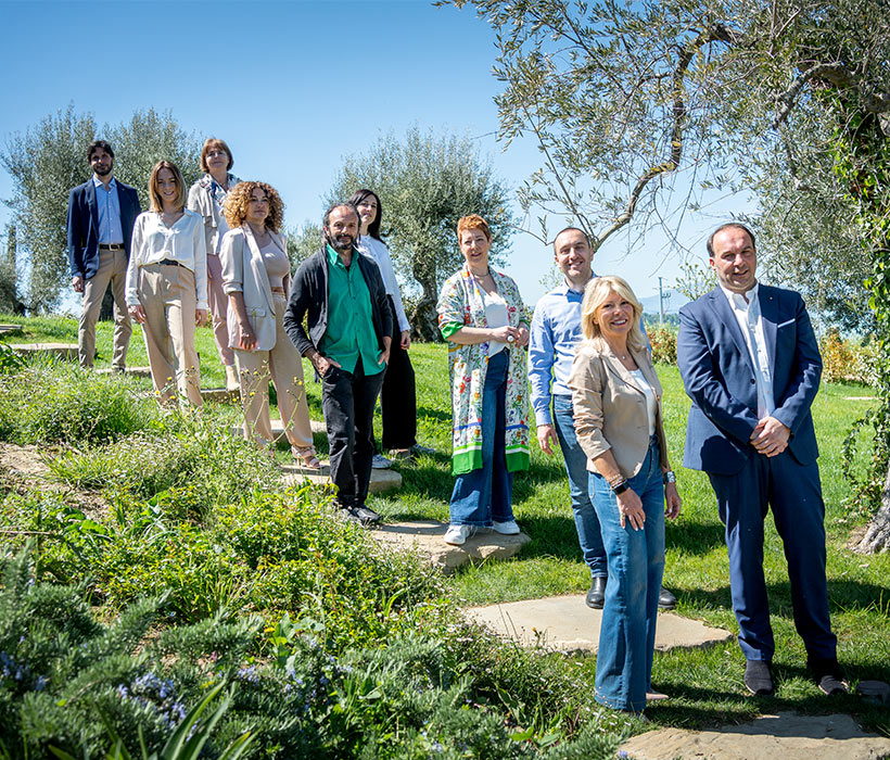 Gruppo di persone in piedi all'aperto su un sentiero in giardino con alberi e vegetazione.