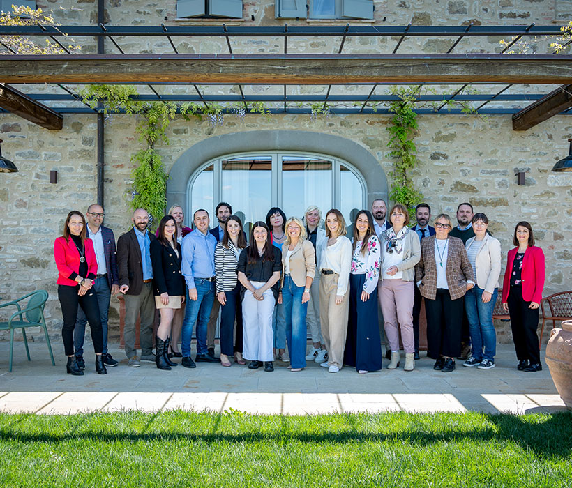 Gruppo di persone che posa davanti a un edificio in pietra con piante rampicanti.