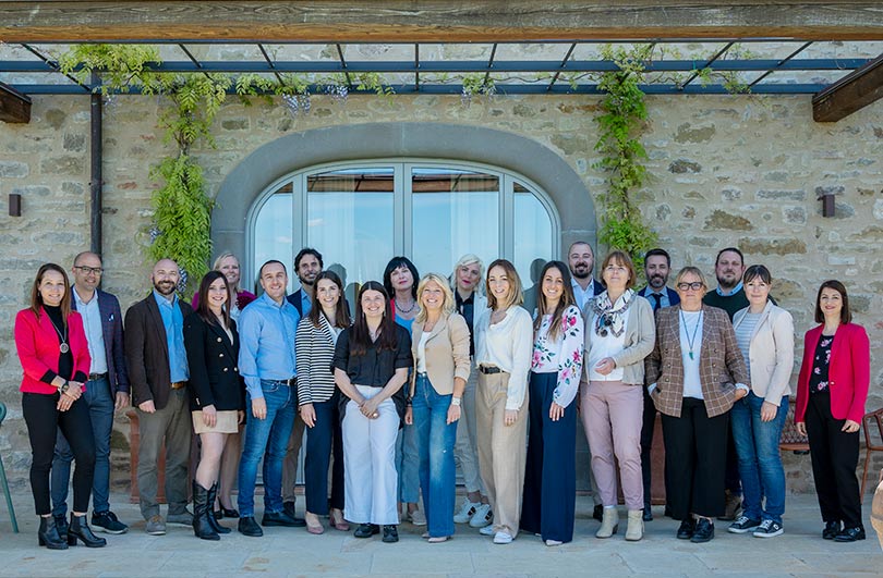 Gruppo di persone in posa davanti a un edificio in pietra con finestra ad arco.