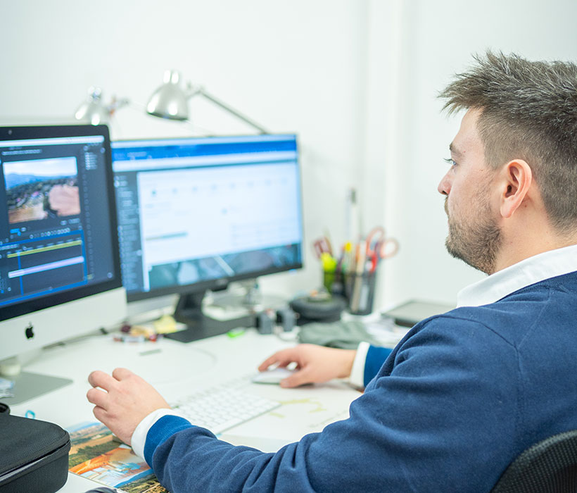 Uomo che lavora al computer con due monitor in un ufficio moderno.